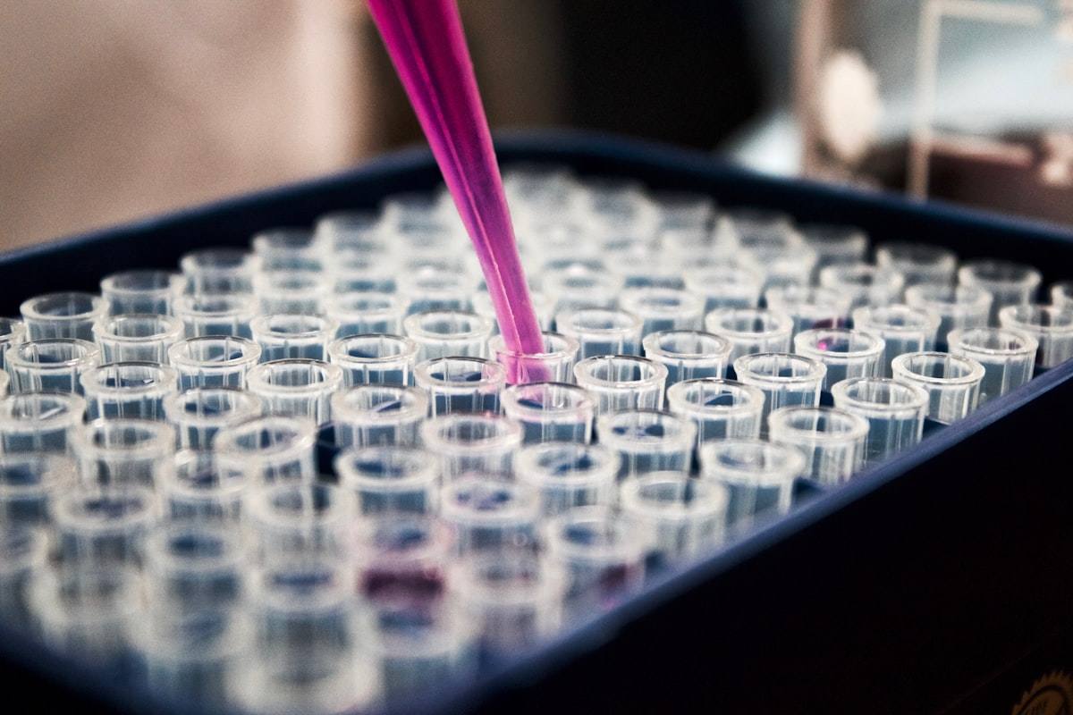 Pipette dispensing liquid into a tray of laboratory test tubes